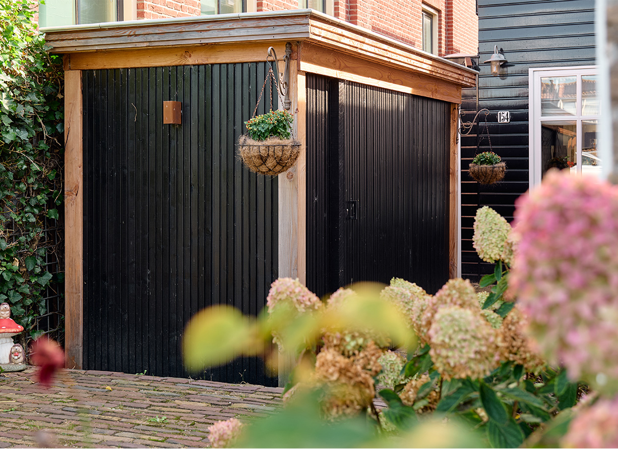 Zwarte berging met hortensia op de voorgrond in tuin aan de IJssel