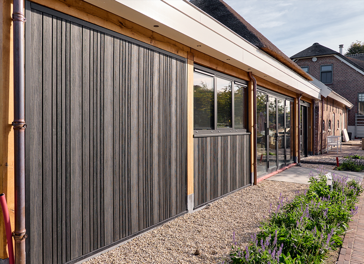 Zwarte houten gevel met ramen en beplanting in Waddinxveen