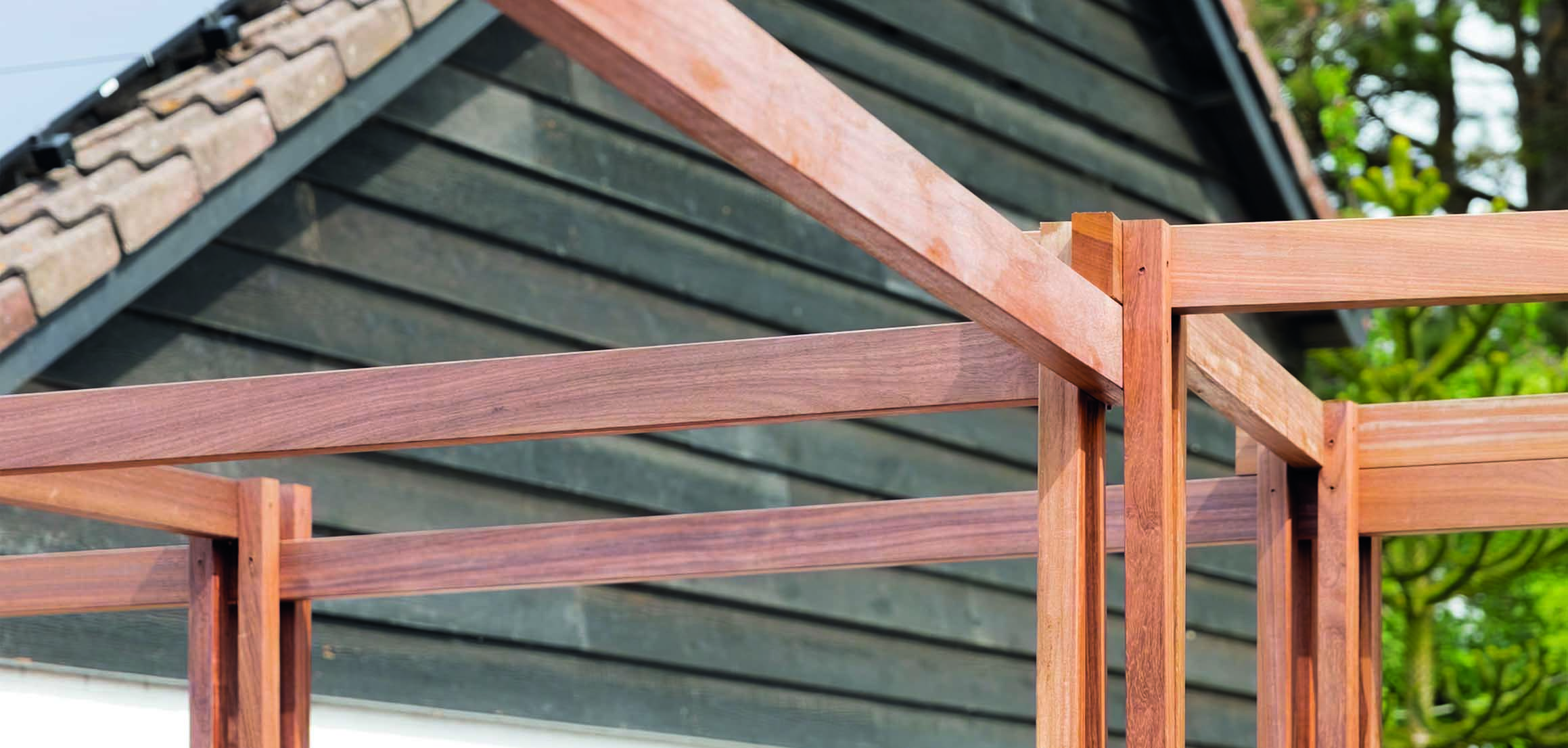 Pergola bij schuur met donkere houten gevel in Oud-Beijerland