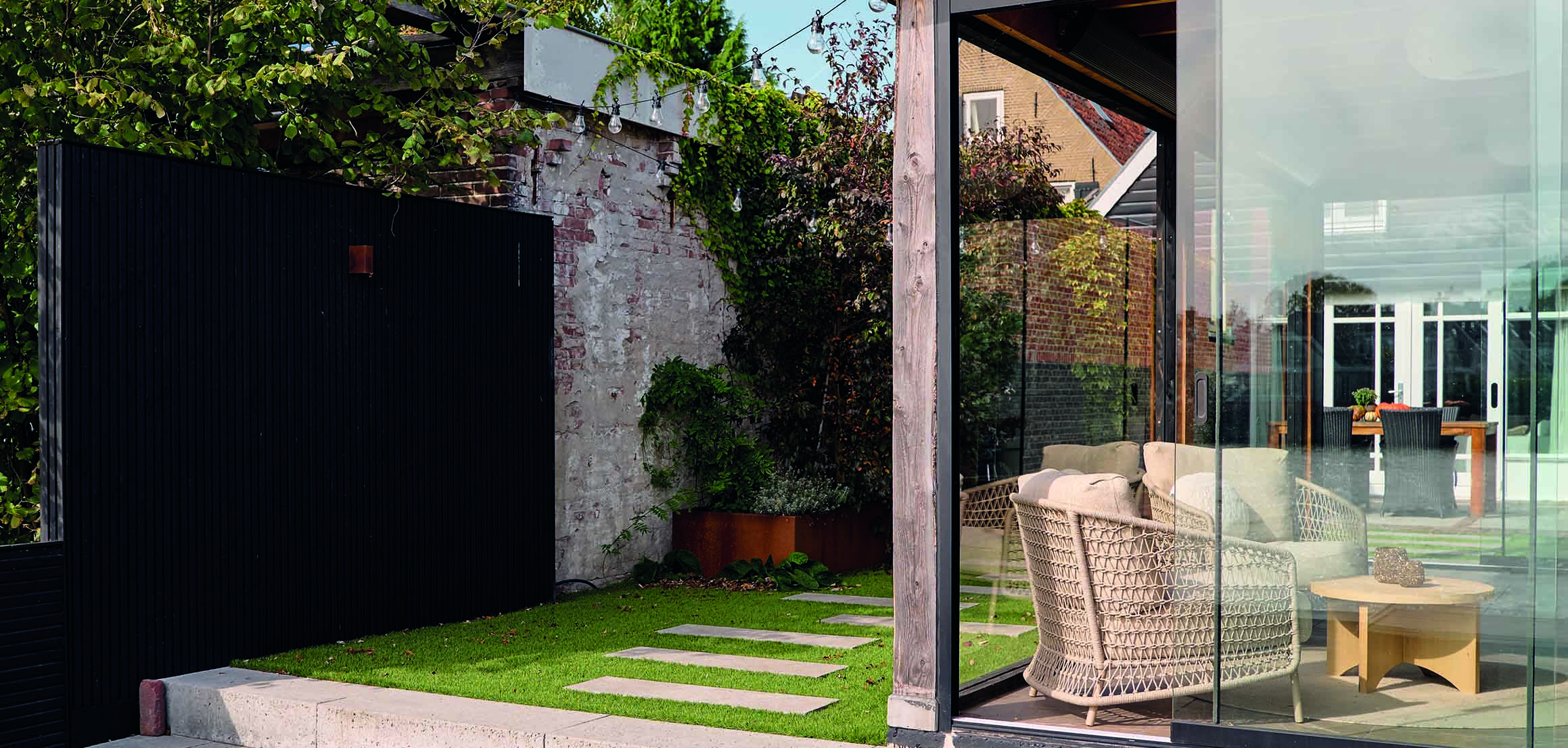 Buitenverblijf met glazen wand en loungestoelen in tuin aan de IJssel