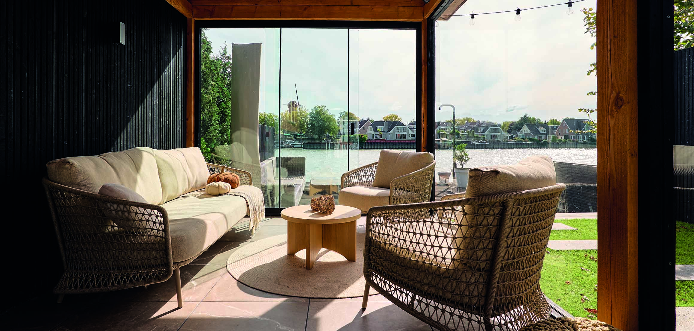 Loungebank in buitenverblijf met uitzicht op het water in tuin aan de IJssel