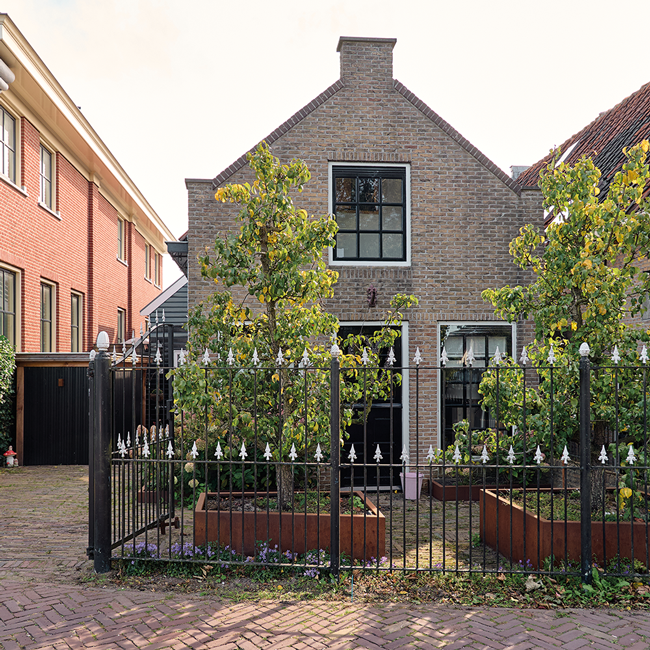 Voortuin met hekwerk en leibomen in tuin aan de IJssel
