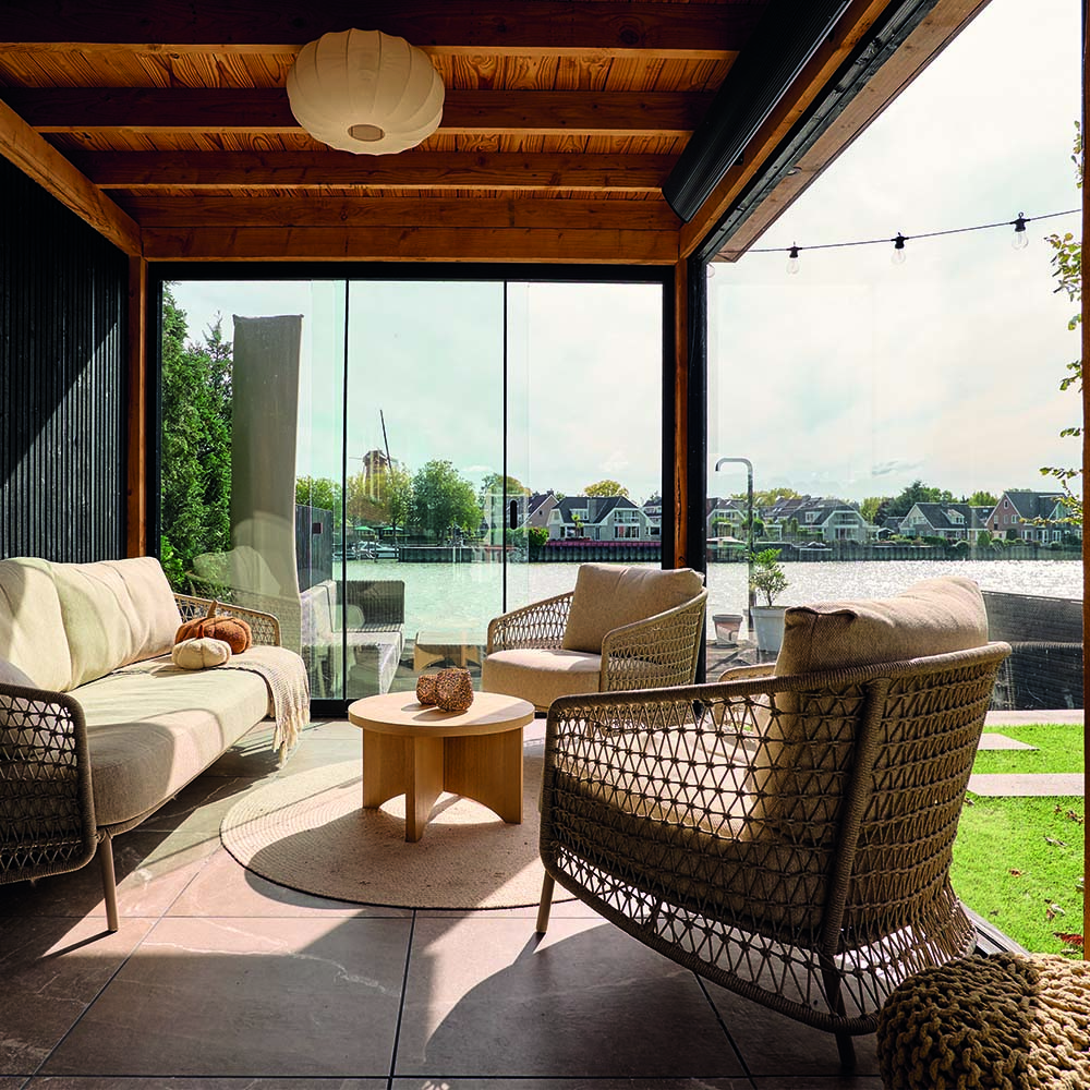 Loungehoek in buitenverblijf aan het water in tuin aan de IJssel