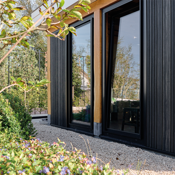 Zwart kozijn met glazen deur en beplanting in Waddinxveen